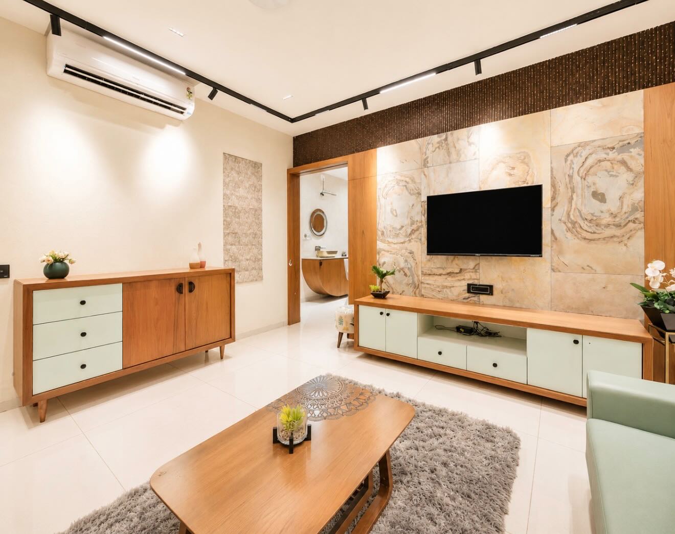 Warm modern living room with teak media unit, sage cabinetry and a stone-veneer feature wall